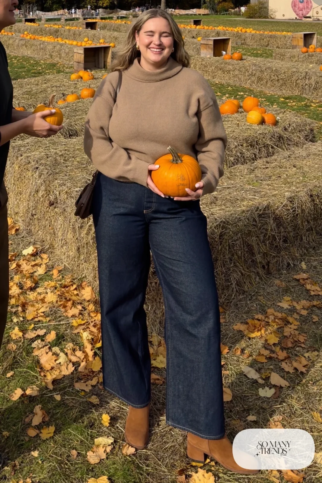 Woman in an oatmeal shawl collar sweater with dark wide-leg jeans and suede ankle boots, outfit 6