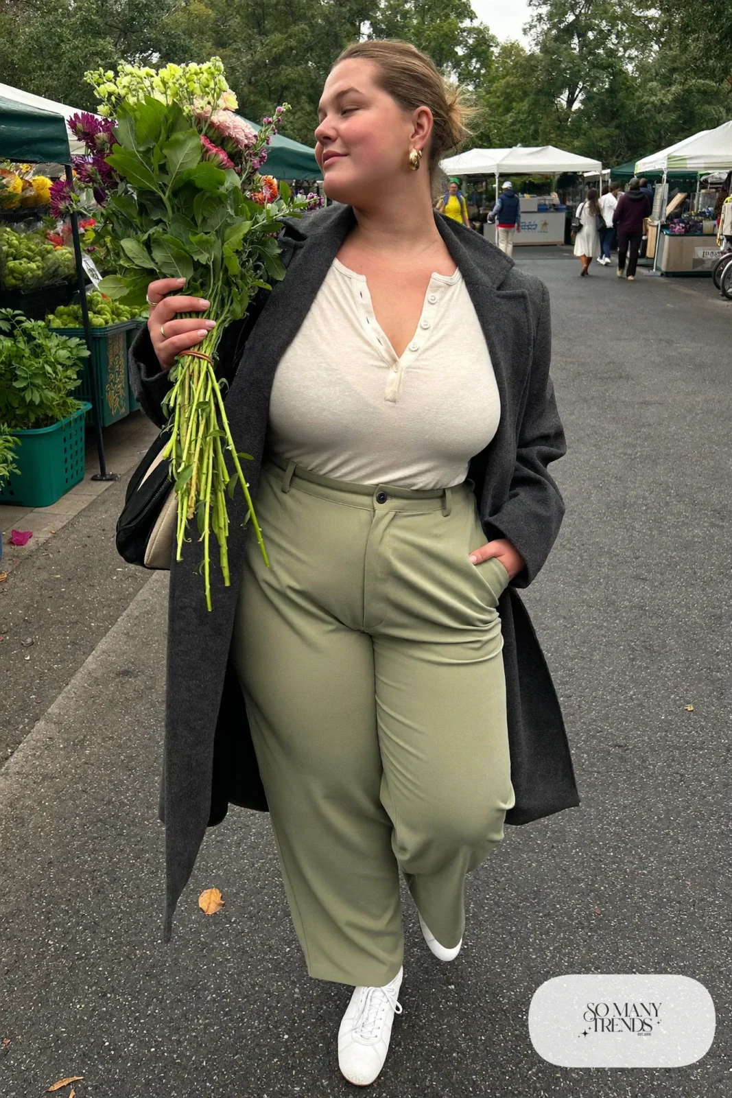 Woman in an oatmeal henley with sage tailored pants, white sneakers and a long coat, outfit 22