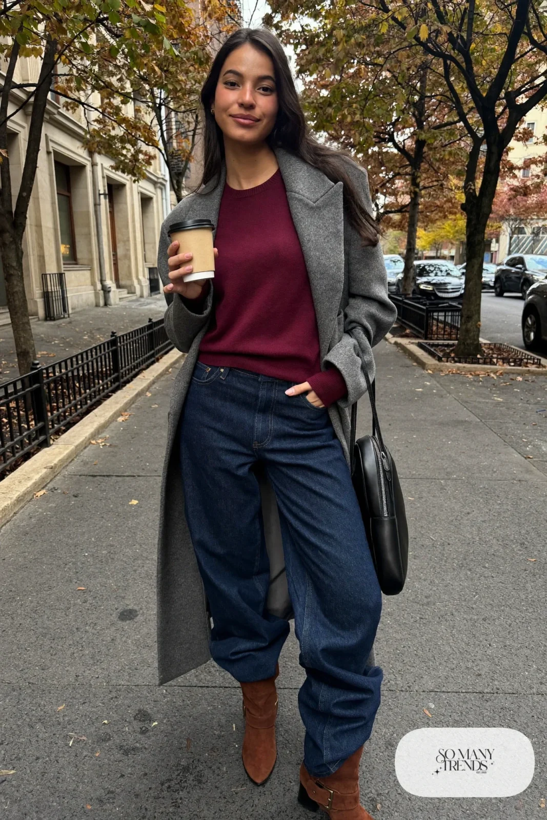 Woman in dark indigo barrel-leg jeans, long charcoal wool coat, burgundy knit sweater and brown suede ankle boots, look 1