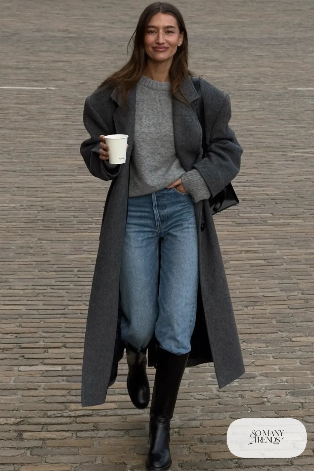 Woman in straight mid-blue jeans tucked into black knee-high boots, gray sweater and wool coat, look 16
