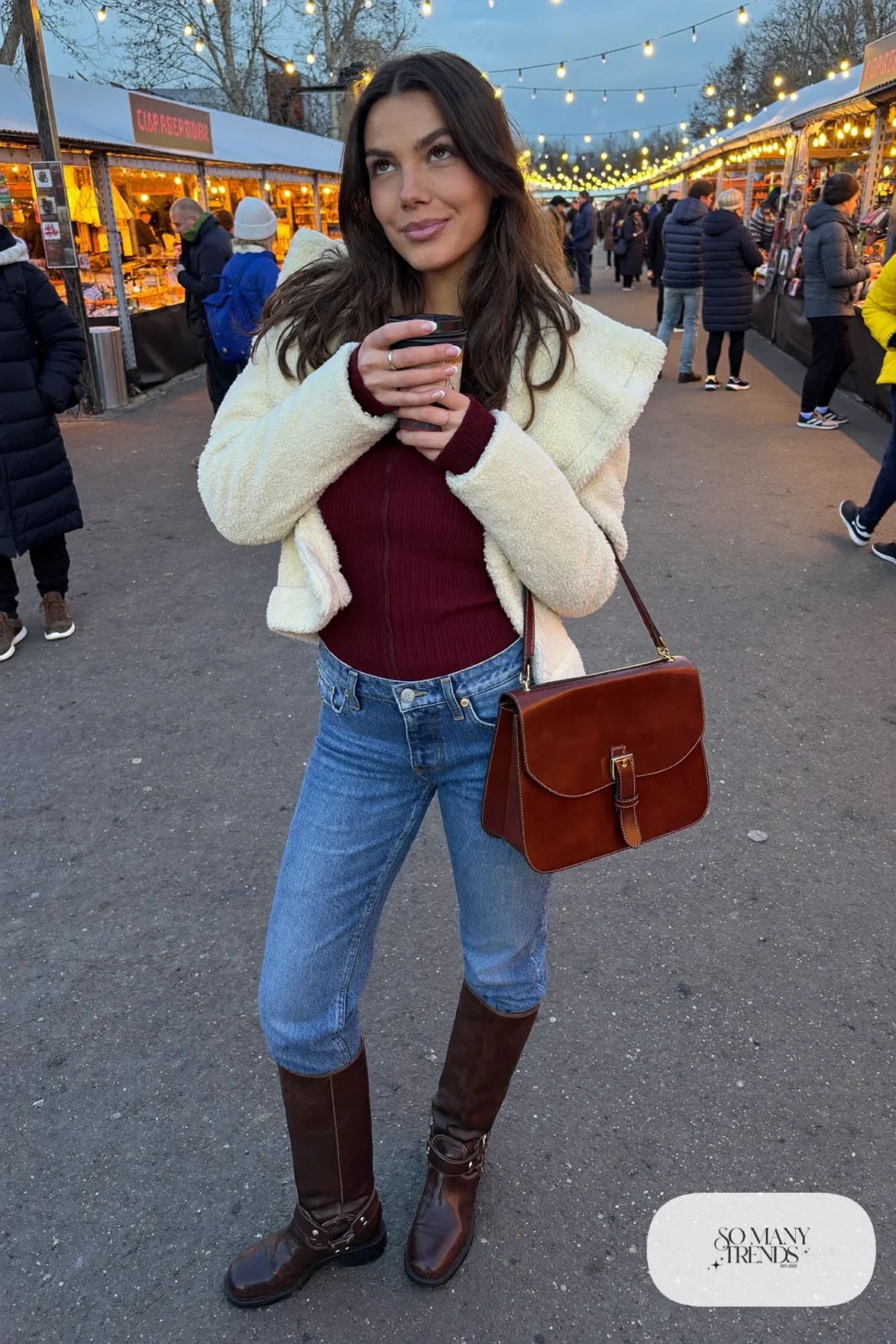 Woman in straight jeans tucked into brown boots, cream sherpa jacket and burgundy knit, look 18