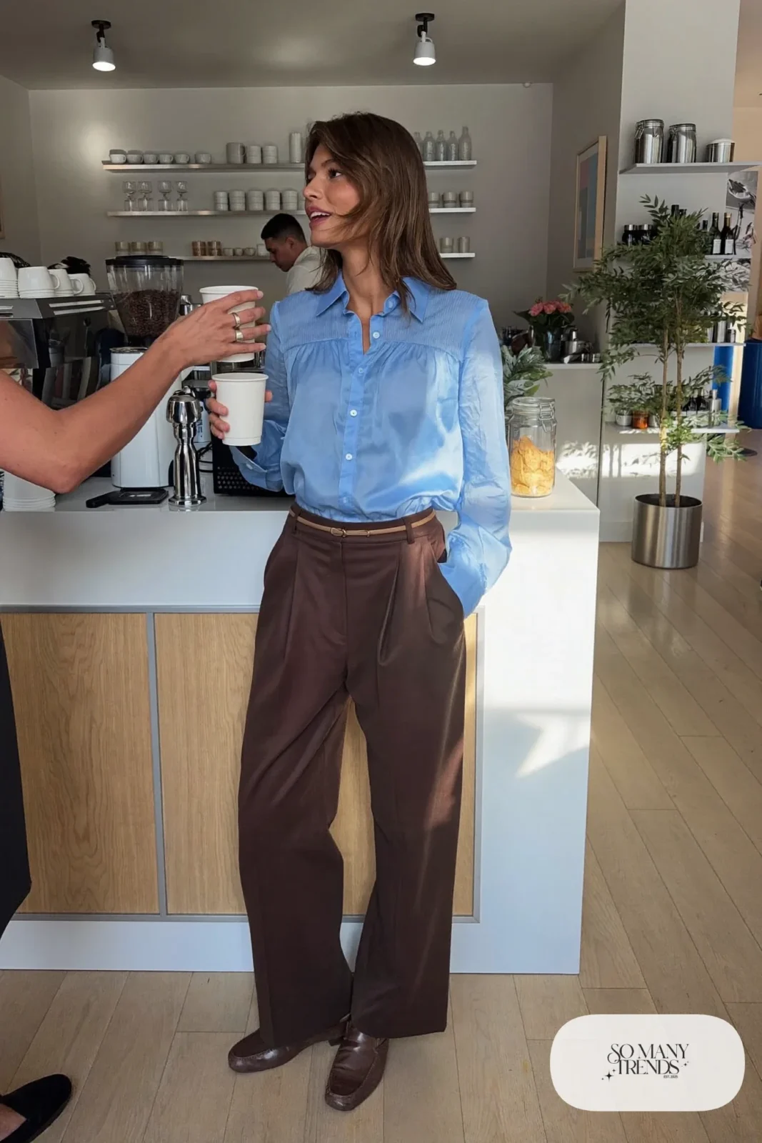 Woman with a straight athletic figure in a baby blue gathered-bust blouse tucked into high-waisted brown pants with a belt, outfit 10