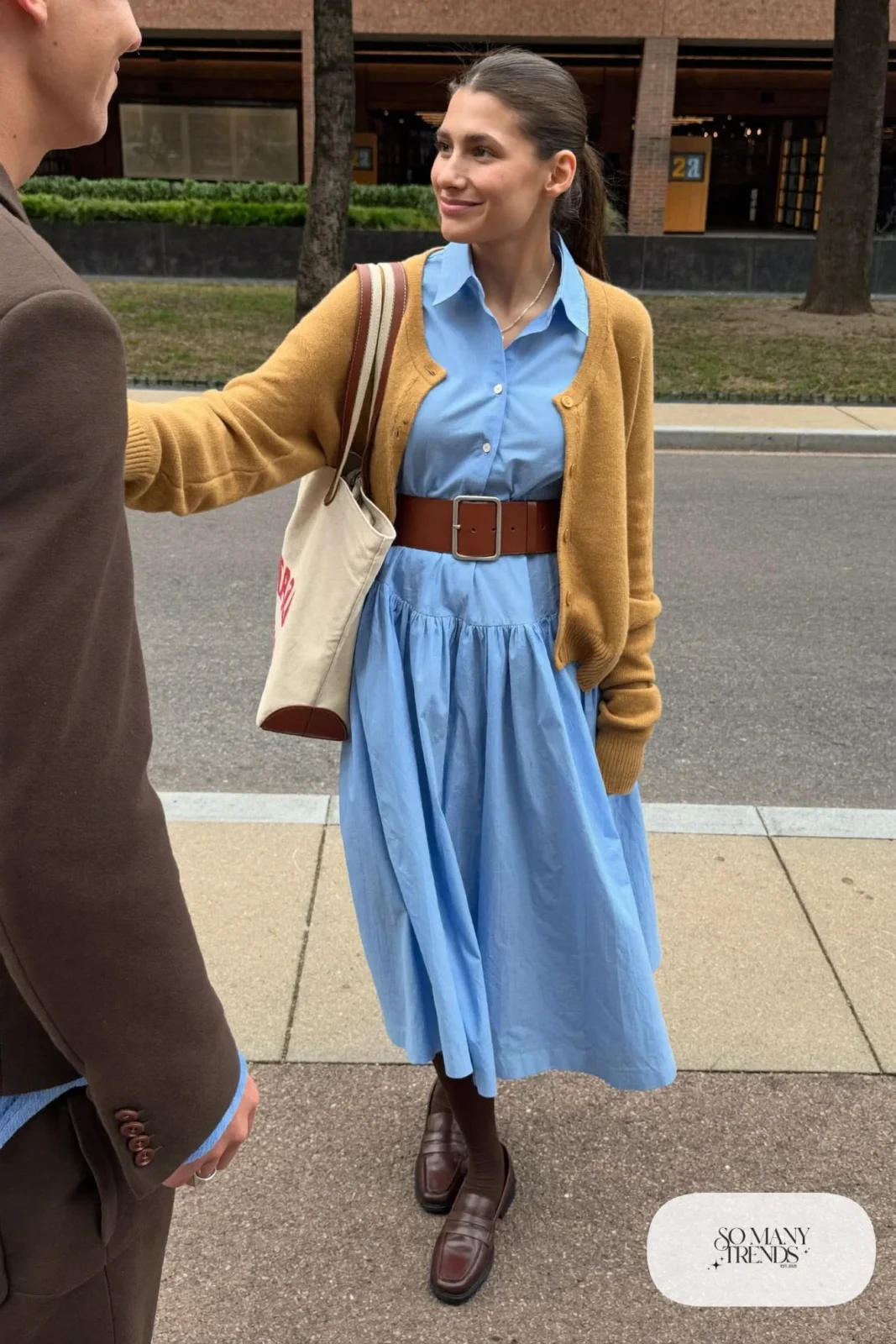 Woman with a straight athletic figure in a baby blue belted shirt dress with a camel cardigan over her shoulders and loafers, outfit 20