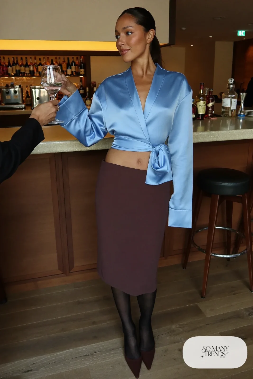 Woman with a straight athletic figure in a baby blue satin wrap blouse, a chocolate pencil skirt and pointed pumps, outfit 23