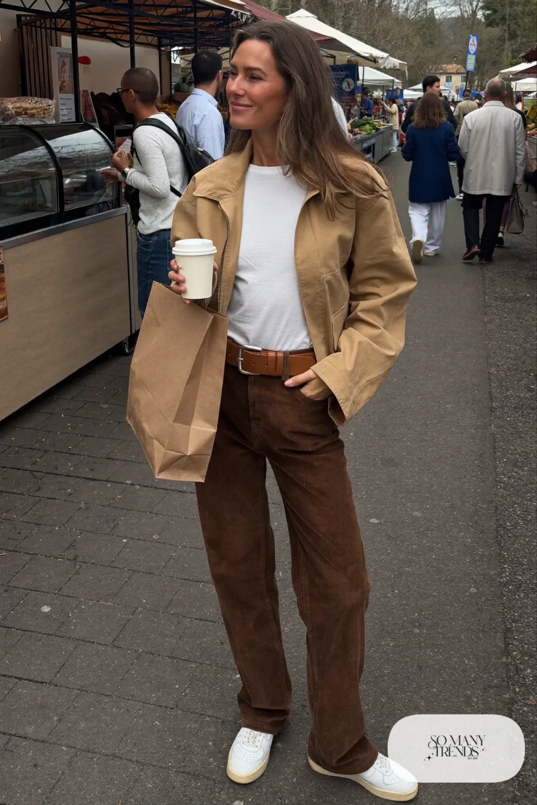 Woman with a straight athletic figure in brown corduroy pants, a white tucked tee, a chunky belt and an oversized sand jacket, outfit 28