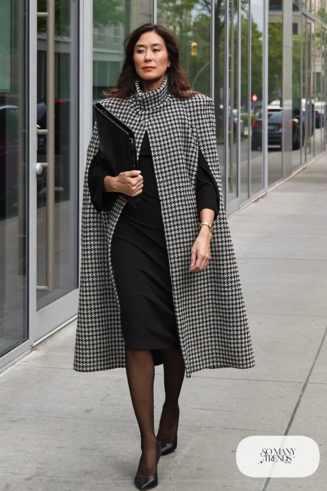 Woman in a black and white houndstooth cape coat over a black sheath dress, sheer black tights and black pointed pumps, outfit 10