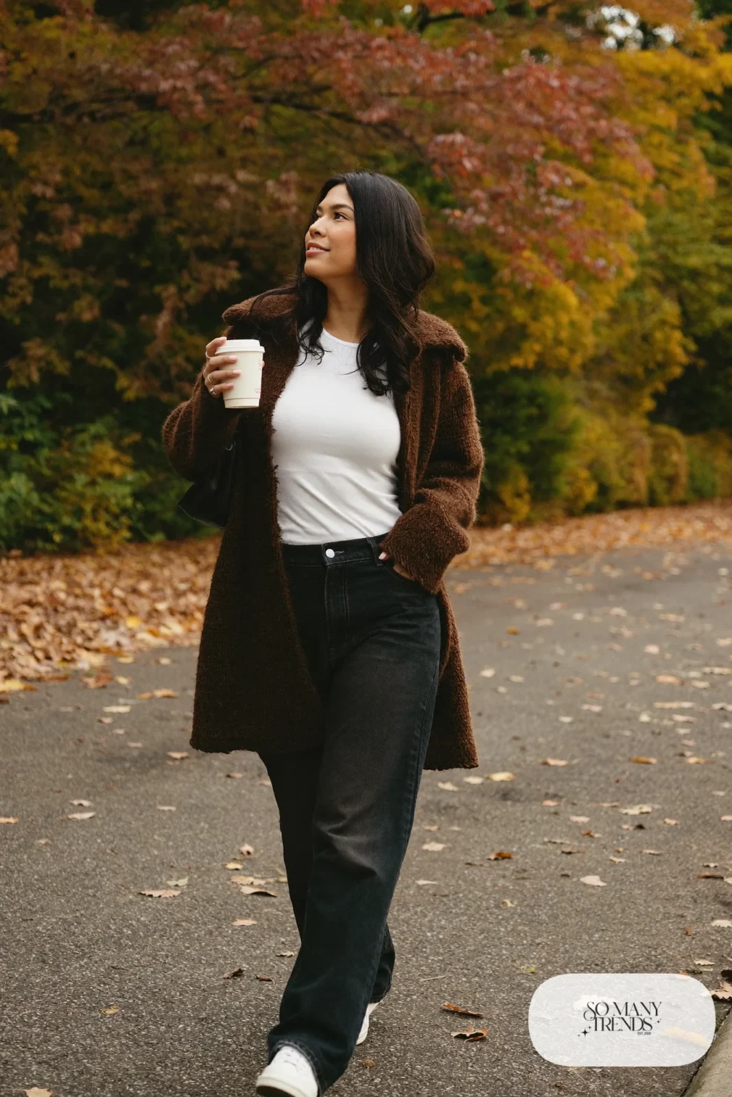 Woman with pear-shaped figure in a long espresso cardigan coat, white tee, dark jeans and white sneakers, outfit 27
