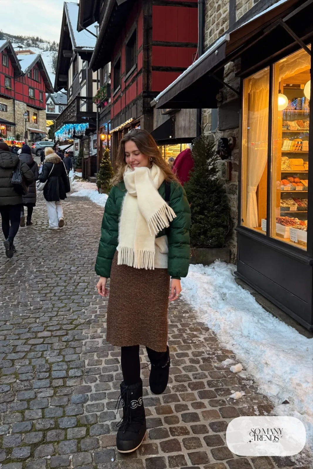 Woman in forest green quilted jacket, brown tweed midi skirt, black opaque tights and black moon boots, outfit 7