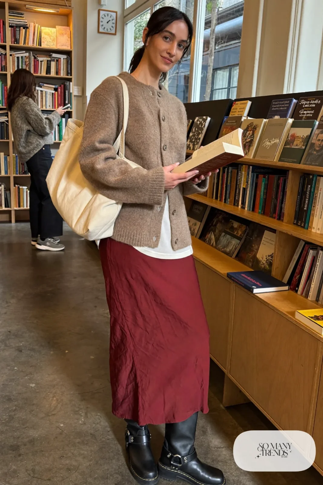 Woman in burgundy satin slip skirt, oatmeal chunky cardigan, sheer black tights and black lug-sole boots, outfit 8