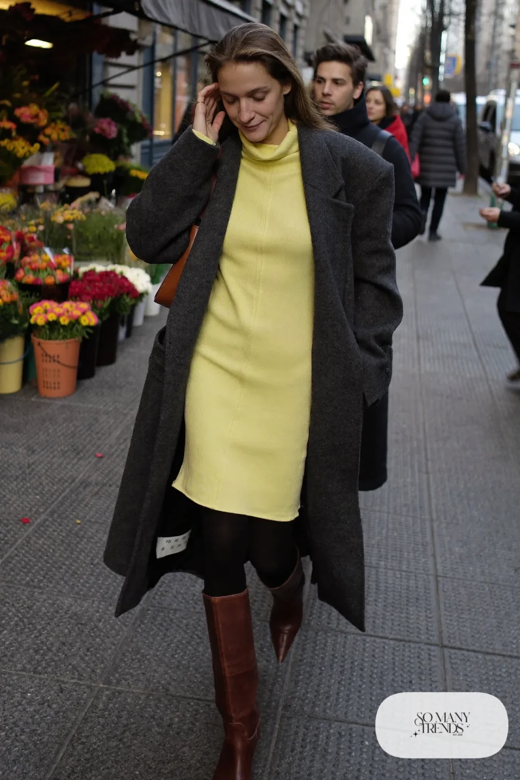 Woman in butter yellow ribbed knit midi dress, long charcoal coat, tall brown boots and a brown leather bag, outfit 18