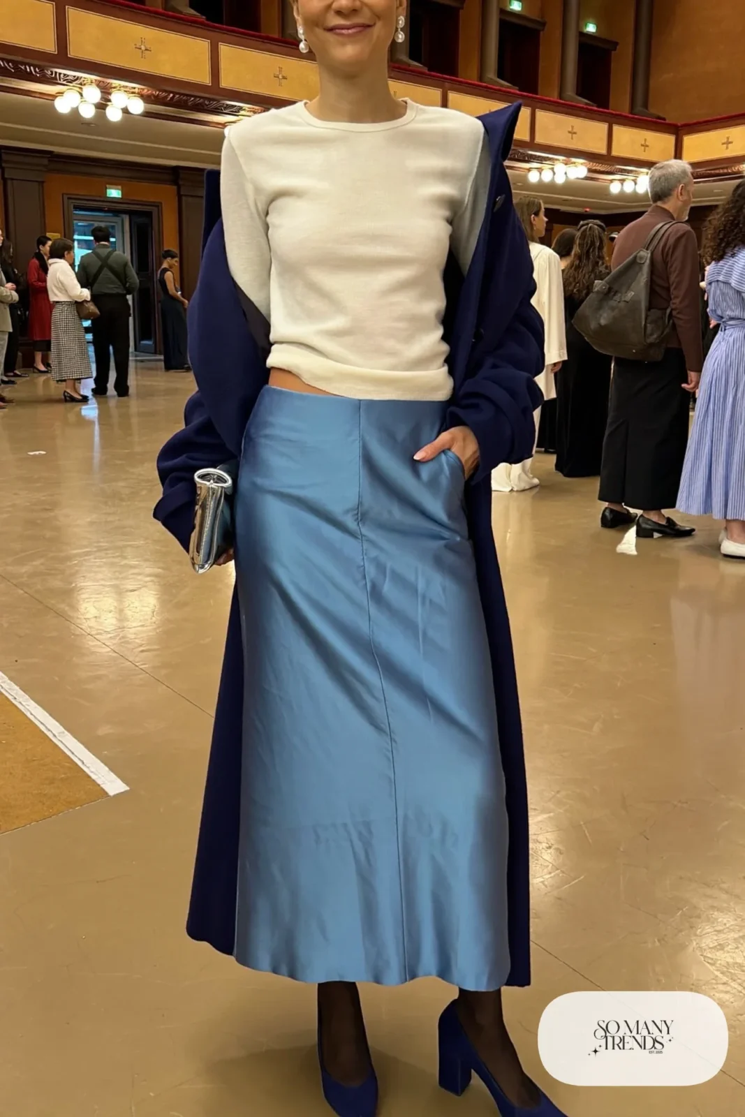 Woman in powder blue satin midi skirt, white fitted knit, navy coat, sheer tights and navy block-heel pumps, outfit 22