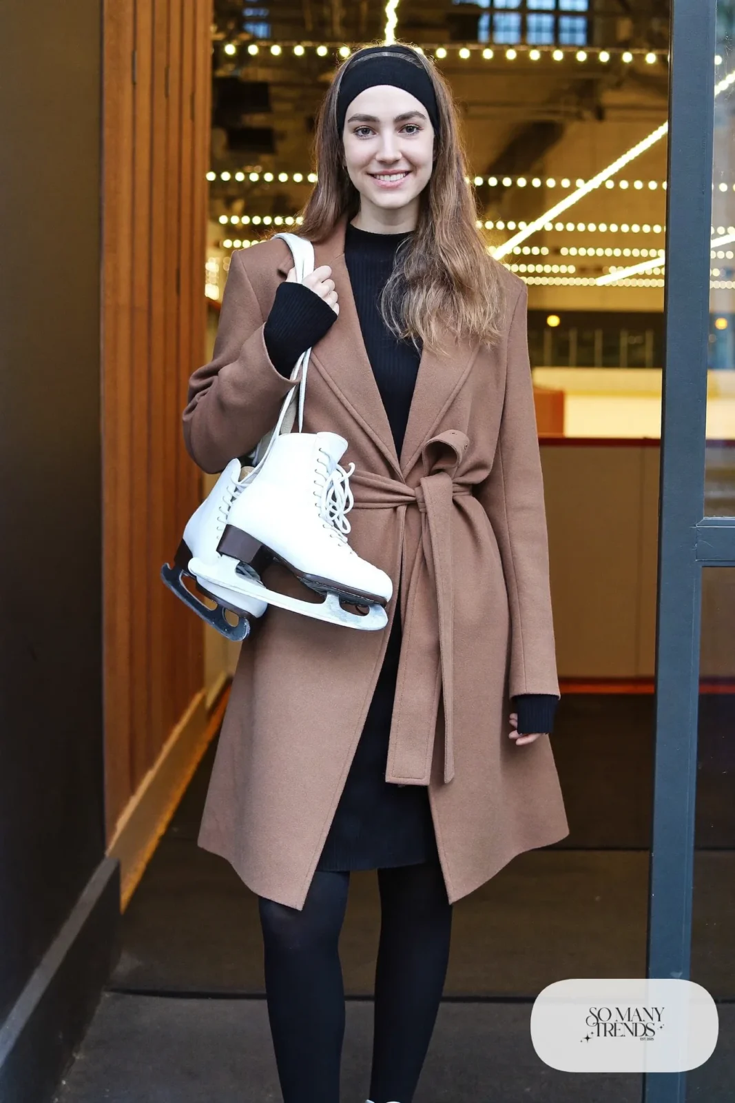 Camel belted wrap coat over black ribbed knit dress, black opaque tights, knit headband and ice skates - outfit 15