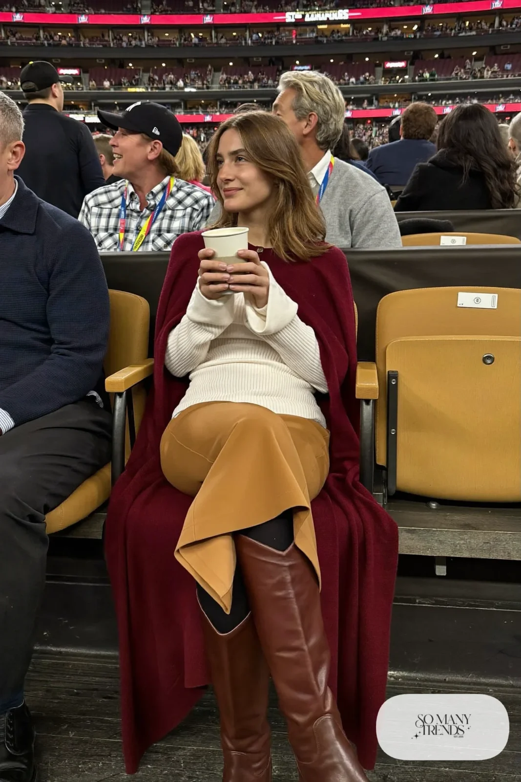 Woman in long burgundy cardigan, cream knit, camel midi skirt and brown boots, NFR outfit 29
