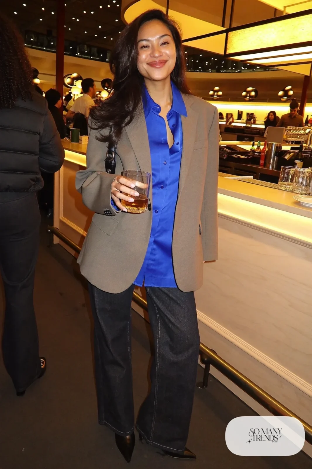 Woman in dark straight jeans, cobalt satin blouse, oatmeal blazer and pointed boots, basketball game outfit 23