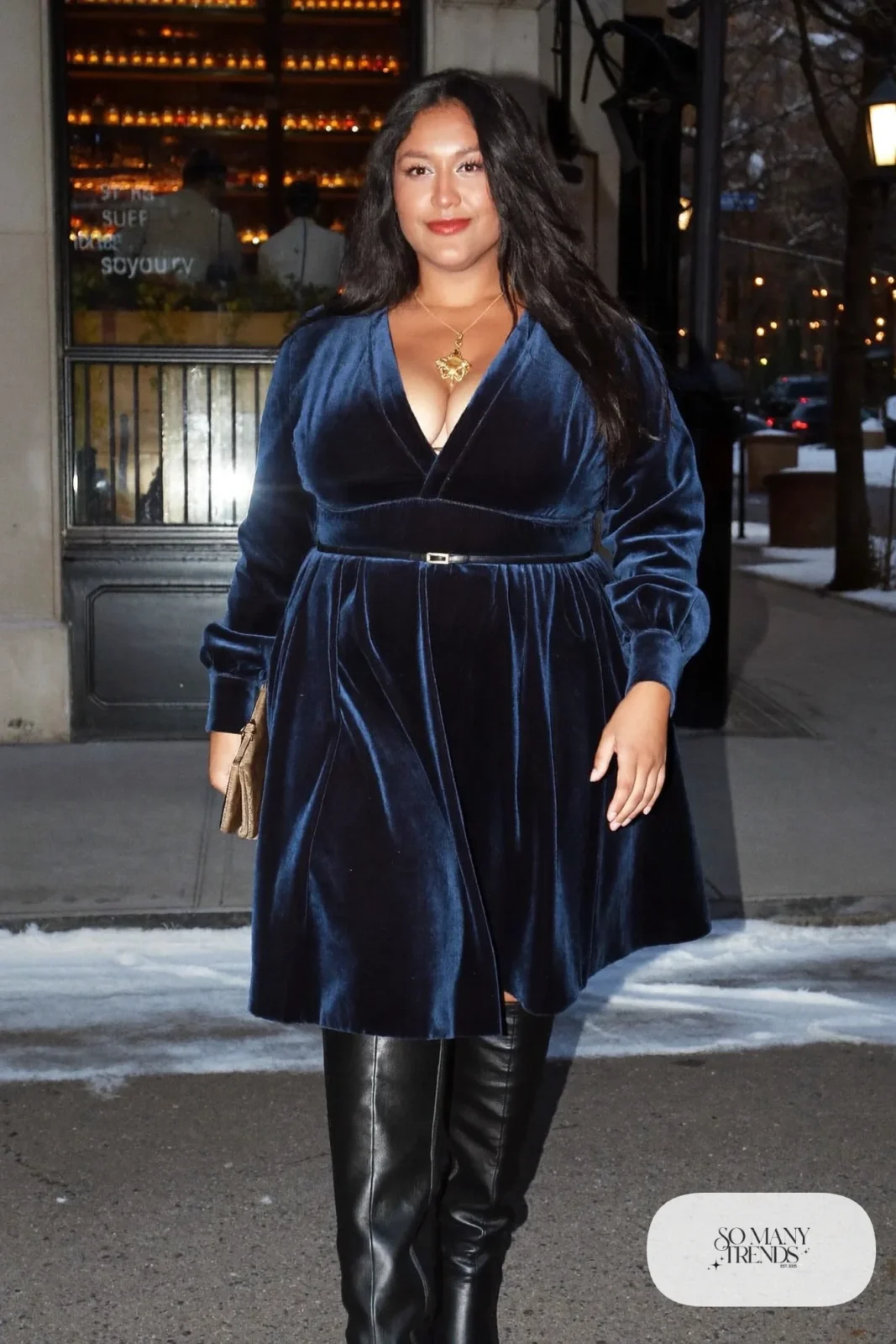 Plus size woman in navy velvet A-line dress with thin belt and black knee-high boots, outfit 2
