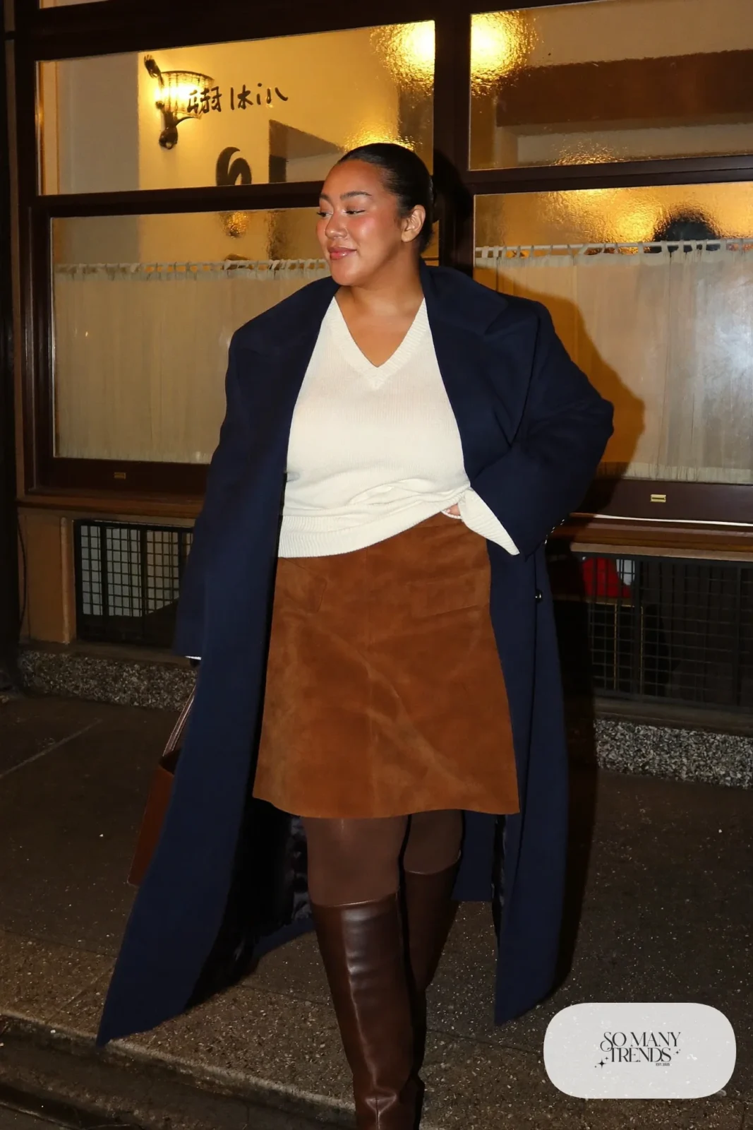 Plus size woman in cognac suede midi skirt, ivory knit, navy coat and dark brown boots, outfit 20