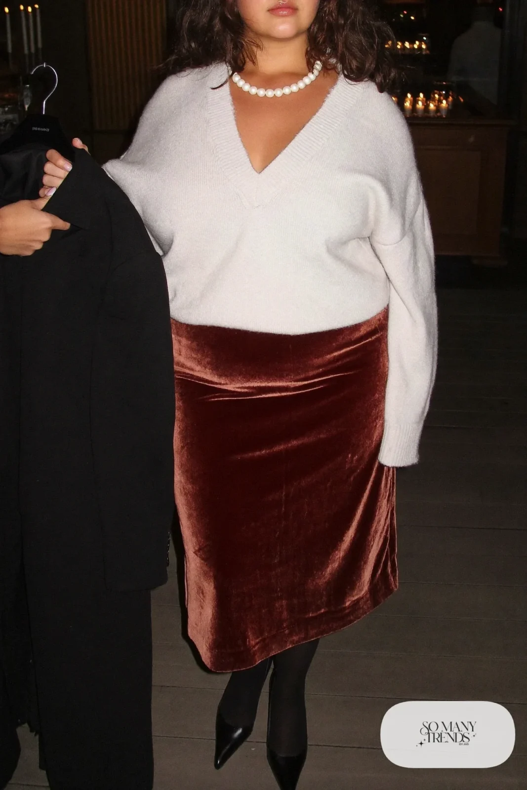 Plus size woman in oxblood velvet midi skirt, ivory knit, black coat and black pointed pumps, outfit 22