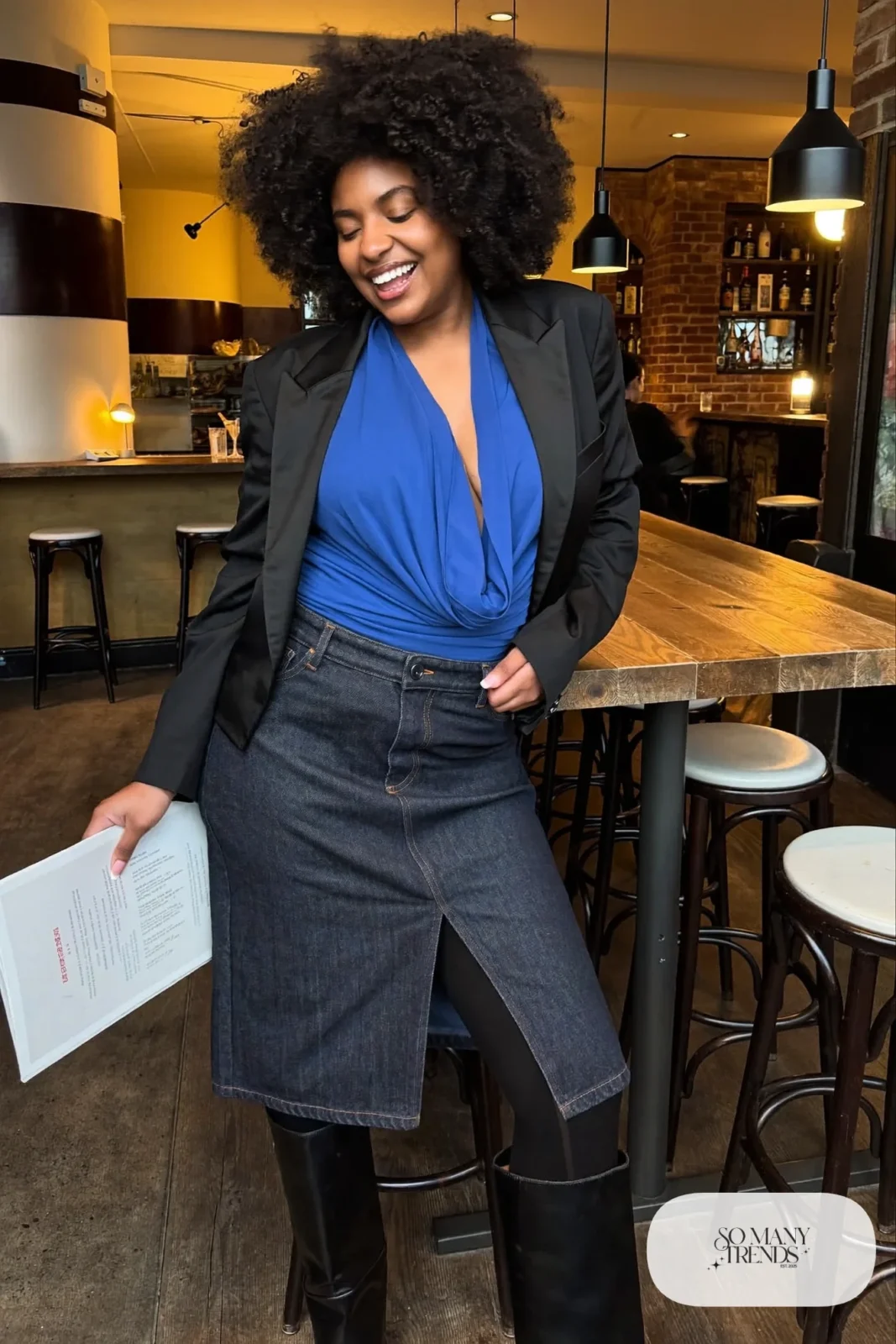 Plus size woman in dark denim midi skirt, cobalt top, black blazer and tall black boots, outfit 23