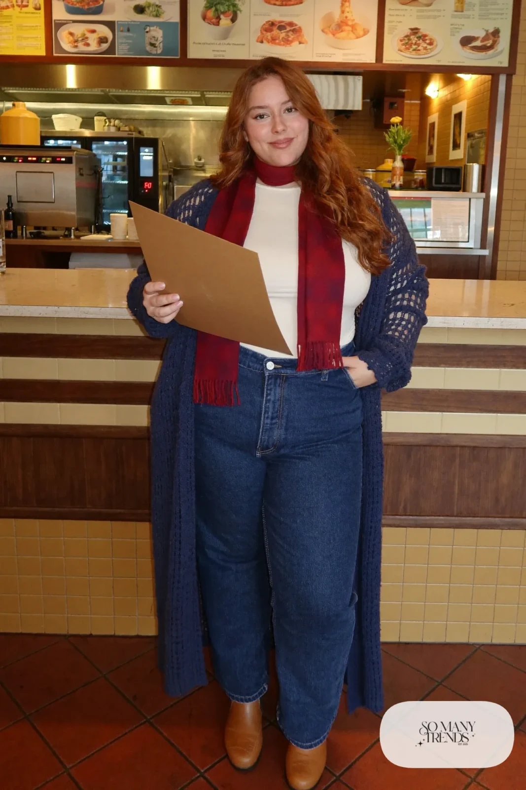 Plus size woman in long navy cardigan, ivory tee, straight jeans, oxblood scarf and brown boots, outfit 25