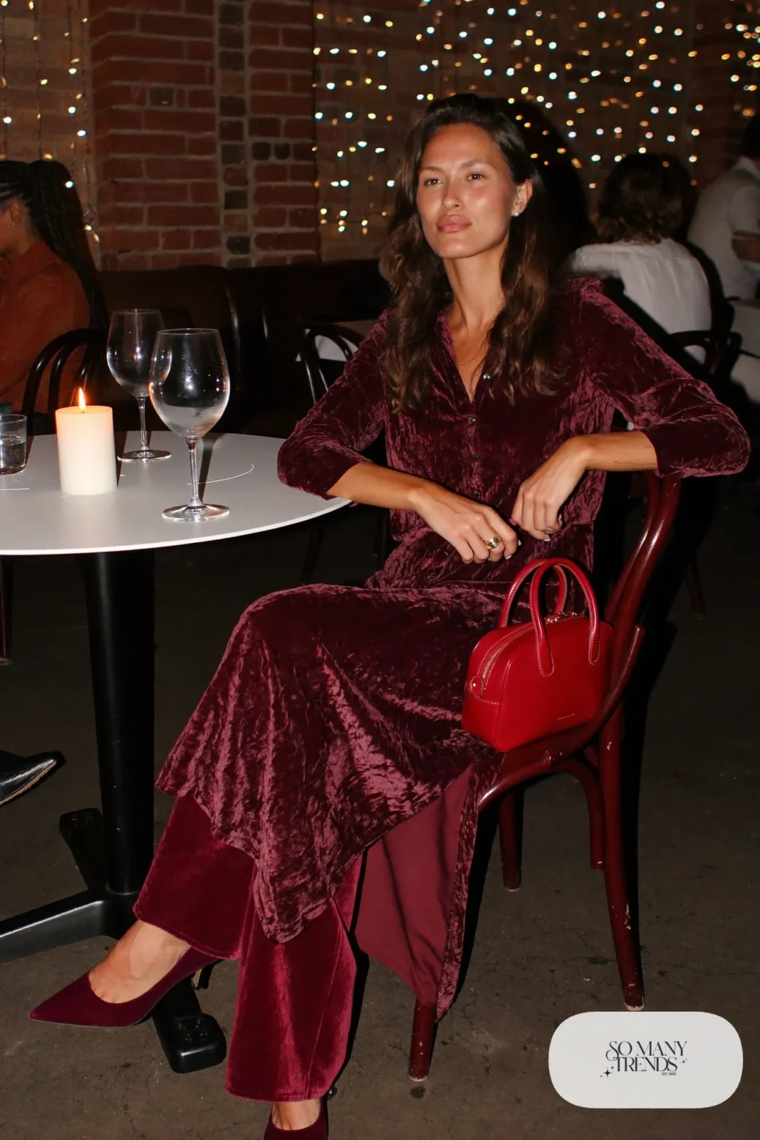 Burgundy crushed velvet tunic with peplum, matching wide-leg velvet pants, red handbag and black pumps, winter date outfit 1