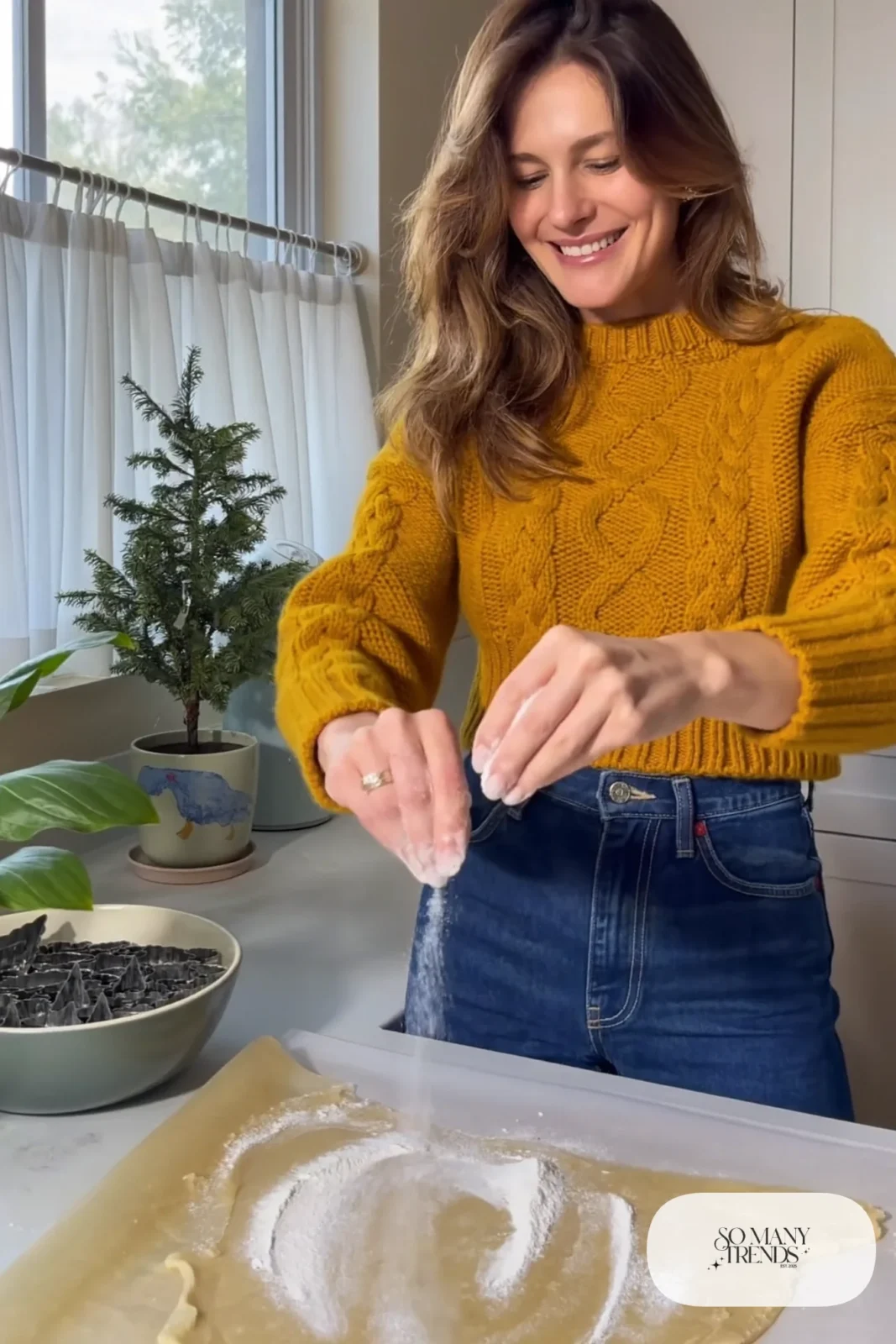 Woman in a chunky mustard knit sweater and dark jeans baking in a bright kitchen, outfit 11