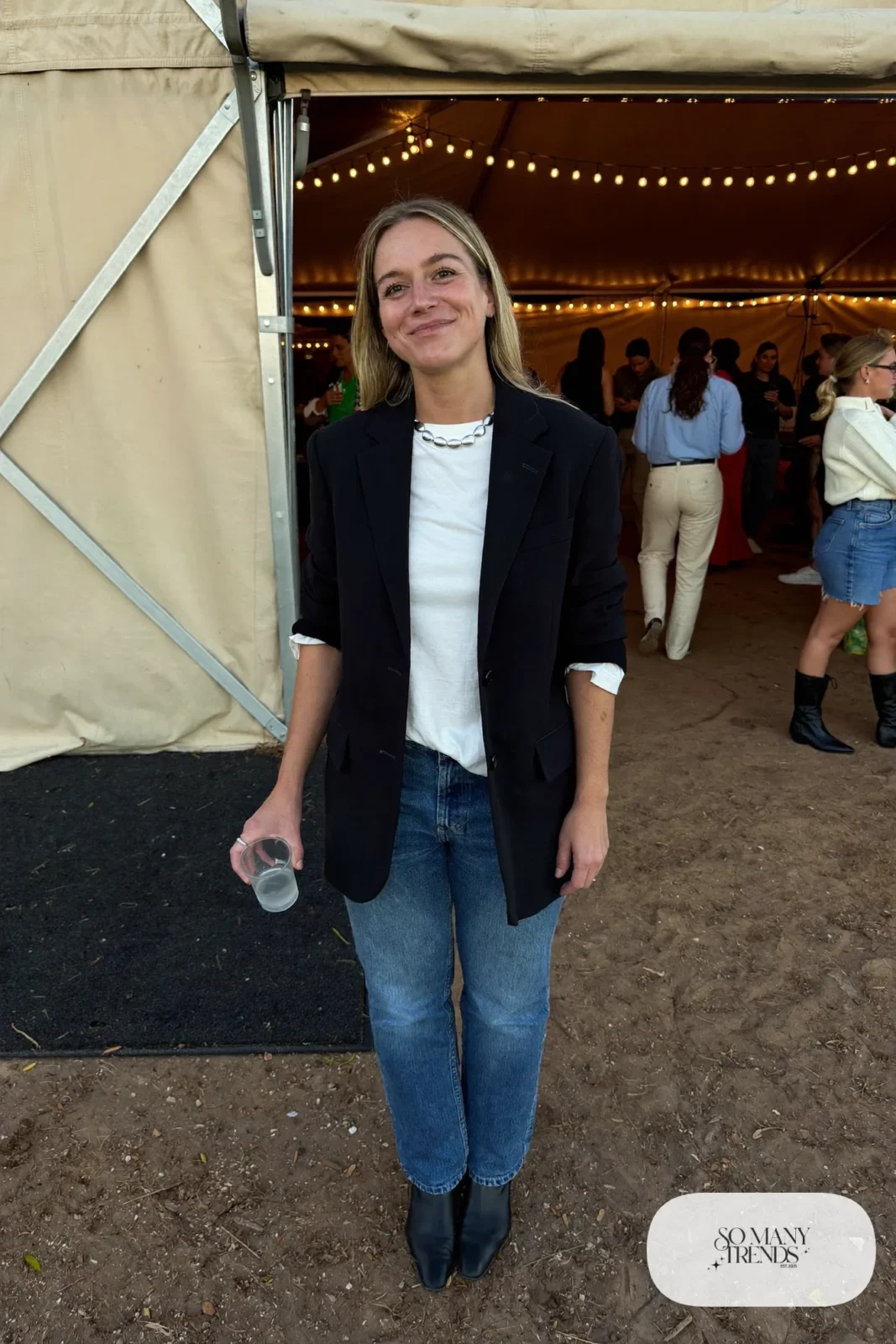 Woman in relaxed black blazer, white tee, straight jeans and black boots with silver necklace, outfit 12