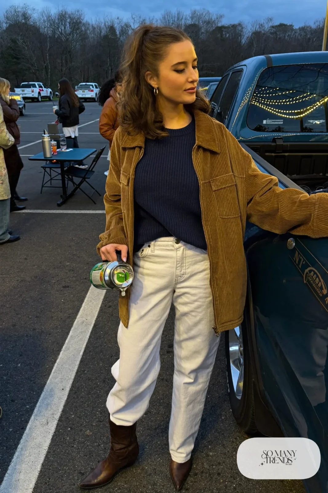 Woman in a cognac corduroy jacket, navy sweater, white straight jeans and brown western boots, concert outfit 4