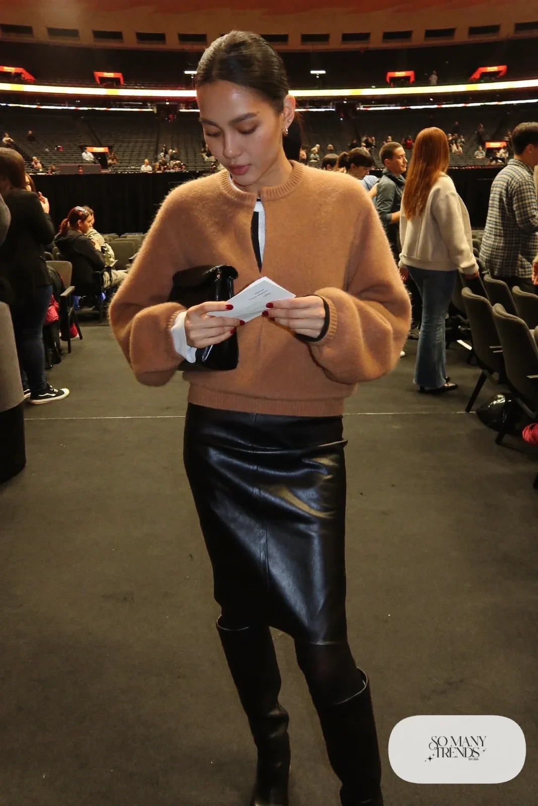 Woman in a camel cardigan, black leather midi skirt, black tights and tall boots, concert outfit 31