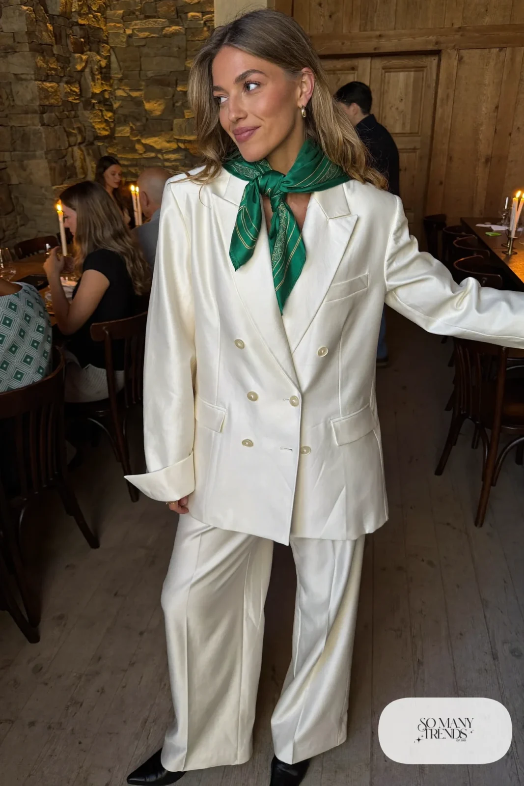 Woman in a pearl wool double-breasted blazer and wide-leg pants set with an emerald silk scarf and black pointed ankle boots at a lodge dinner, outfit 24