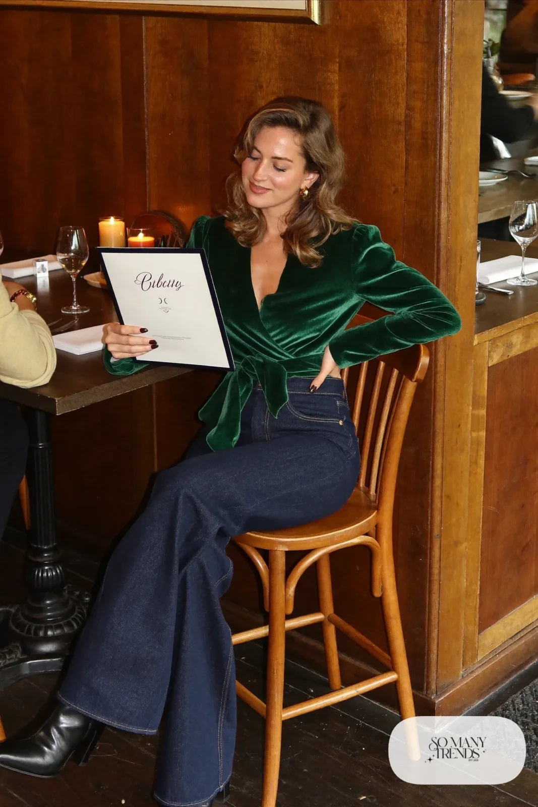 Look 8: forest green velvet wrap top, dark wash wide-leg jeans, gold hoop earrings, black heeled ankle boots