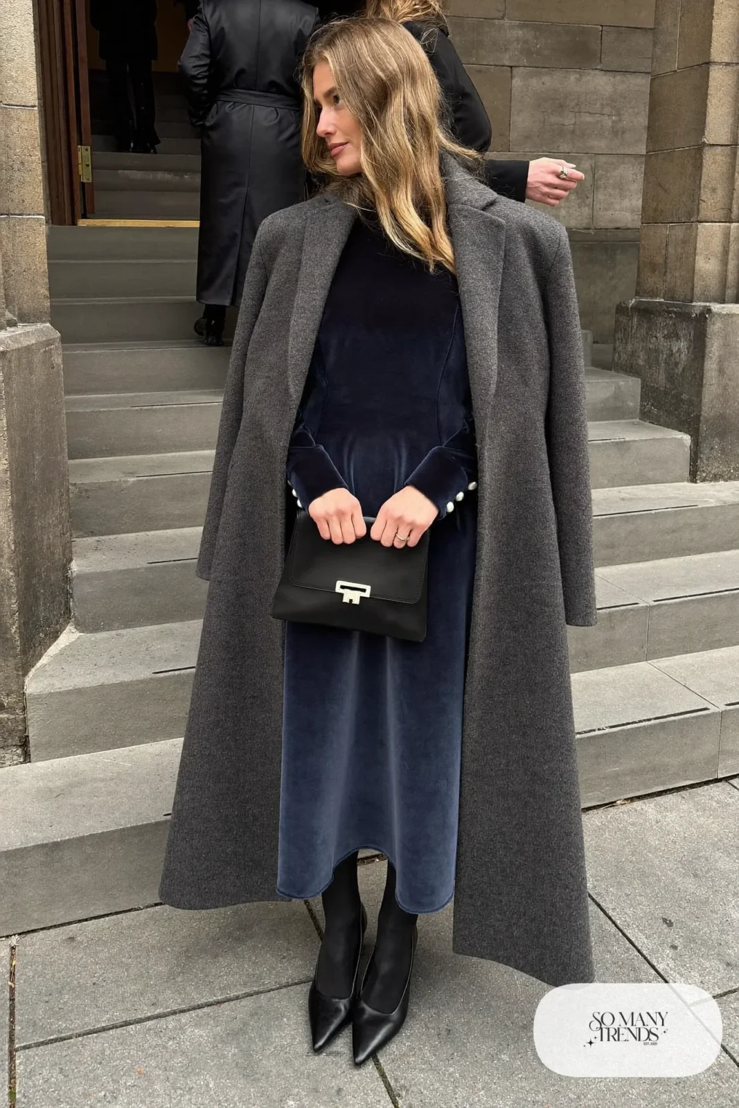 navy velvet long-sleeve midi dress with pearl button cuffs, sheer black tights, black pumps, charcoal wool cape coat, winter wedding guest outfit 7
