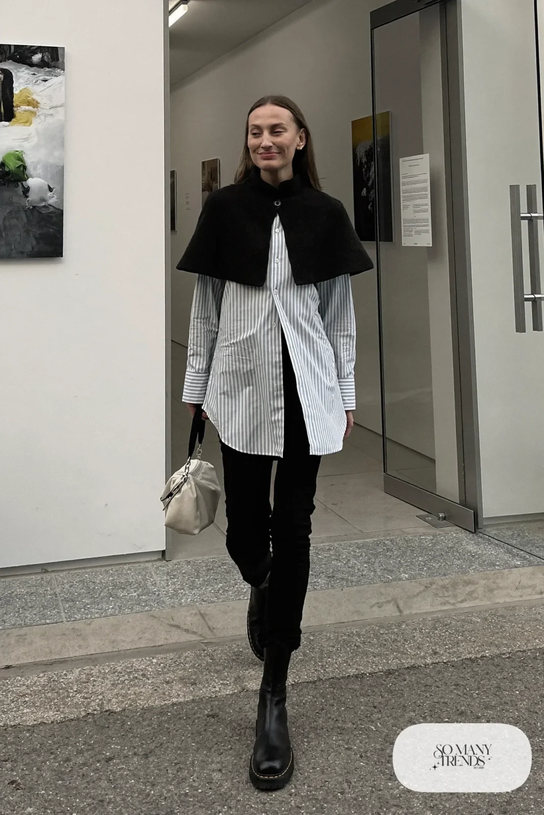 Look 3: black knit capelet over a long blue and white striped shirt, black pants, black lug ankle boots and a cream pouch bag
