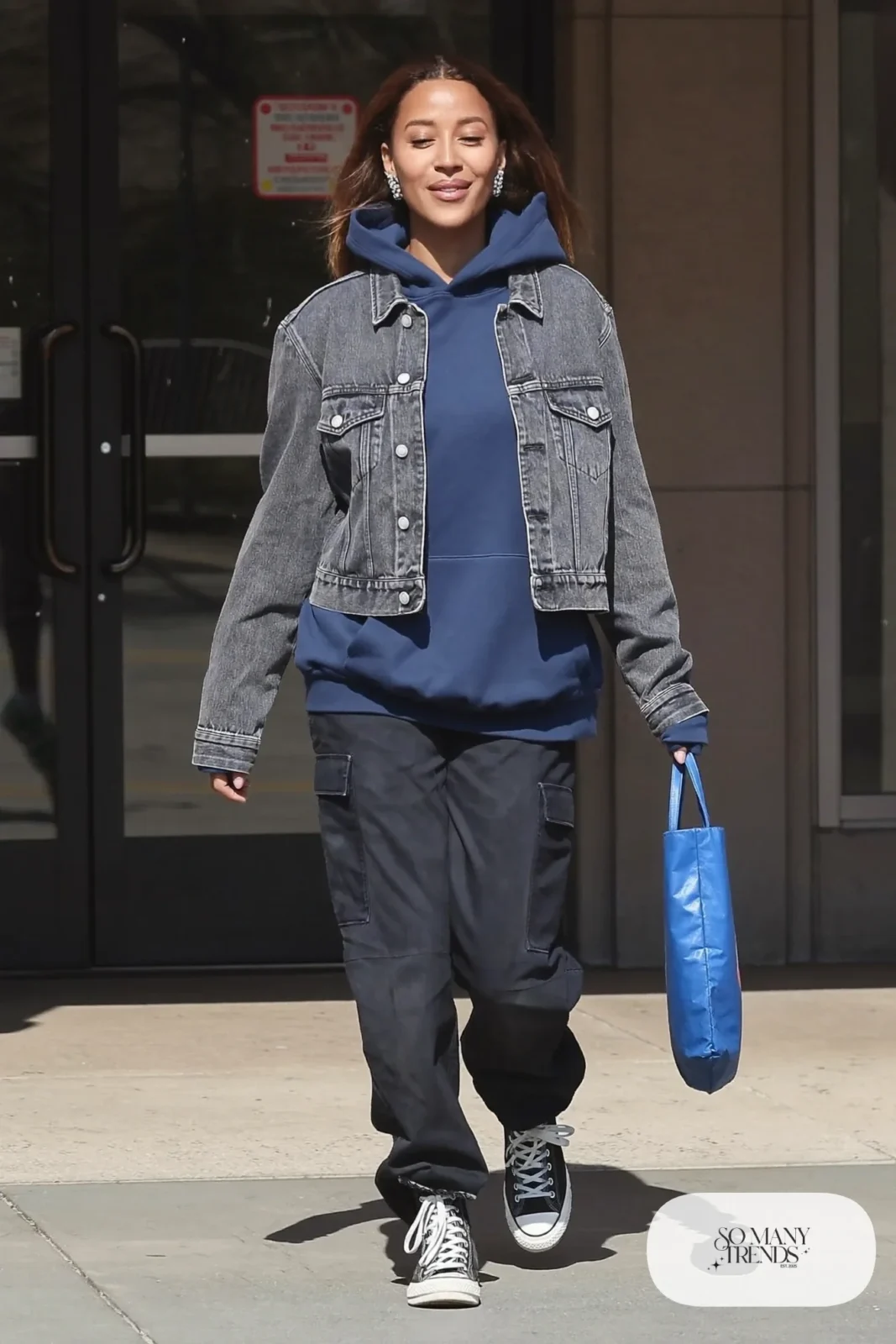 Woman in a navy hoodie, washed black denim jacket, black cargo pants and black high-top sneakers, outfit 4