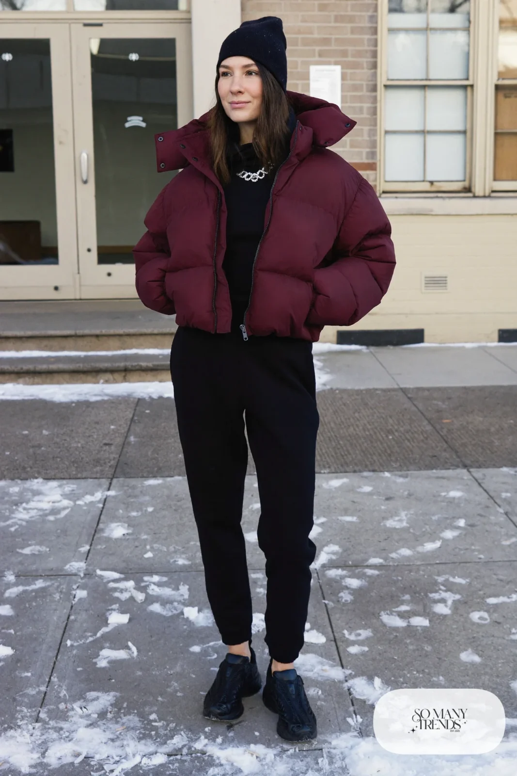 Woman in a cropped oxblood puffer jacket, black fitted tee, black joggers and chunky black sneakers, outfit 7