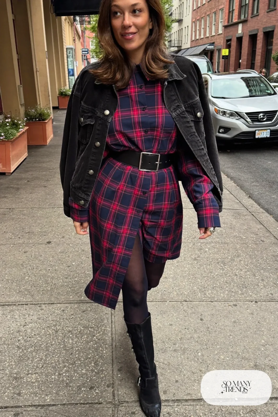 Woman in a navy and red plaid shirt dress with wide belt, black denim jacket, thick tights and tall black boots, outfit 15