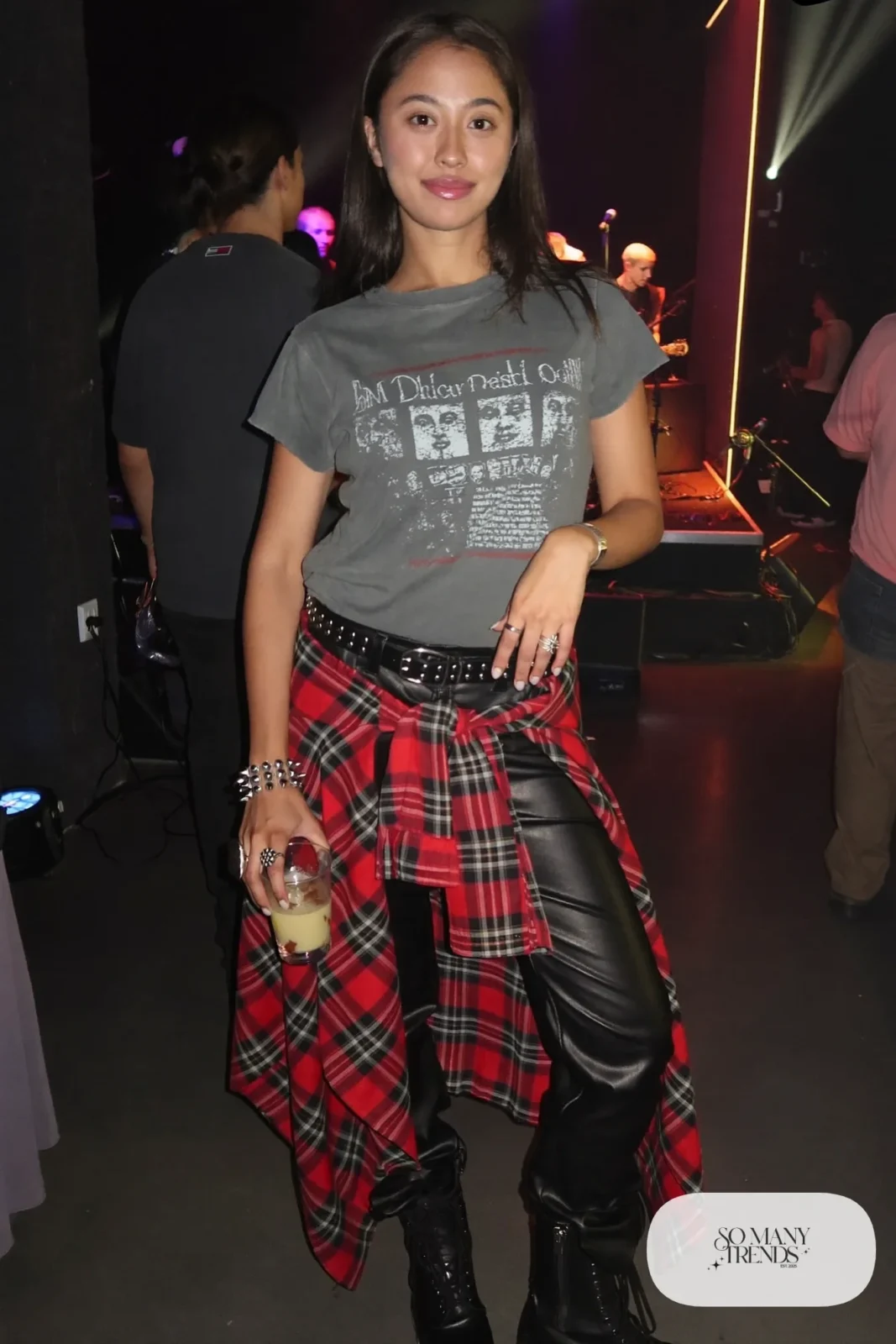 Woman in black faux leather pants, vintage band tee, tied flannel, studded belt and combat boots, outfit 21