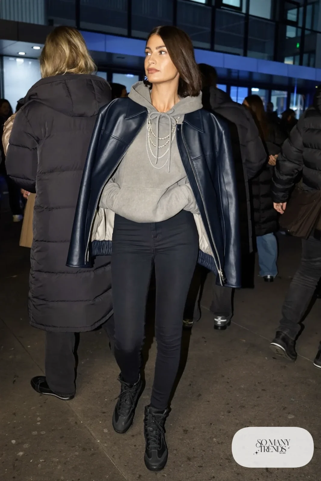 Woman in a navy faux leather jacket, gray band hoodie, black skinny jeans and black high-top sneakers, outfit 24