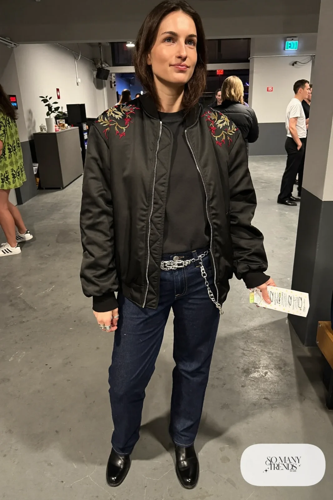 Woman in a black embroidered bomber jacket, black tee, straight jeans and black Chelsea boots, outfit 26