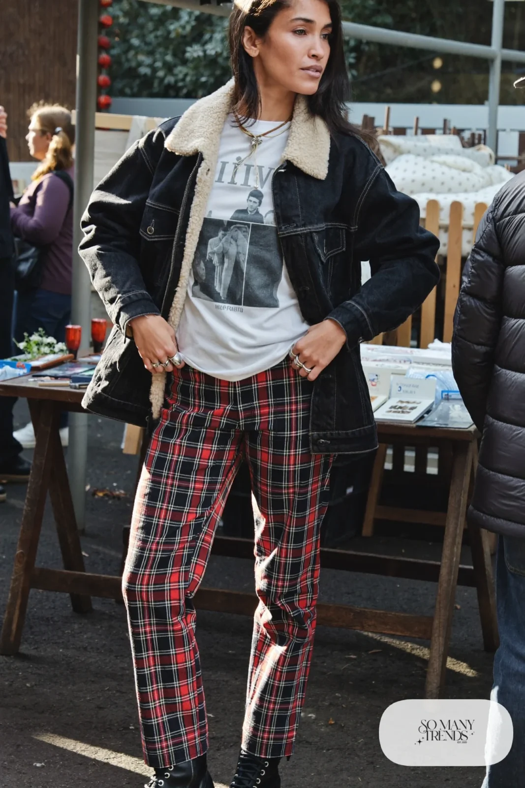 Woman in a sherpa-lined black denim jacket, white band tee, red plaid pants and black combat boots, outfit 29