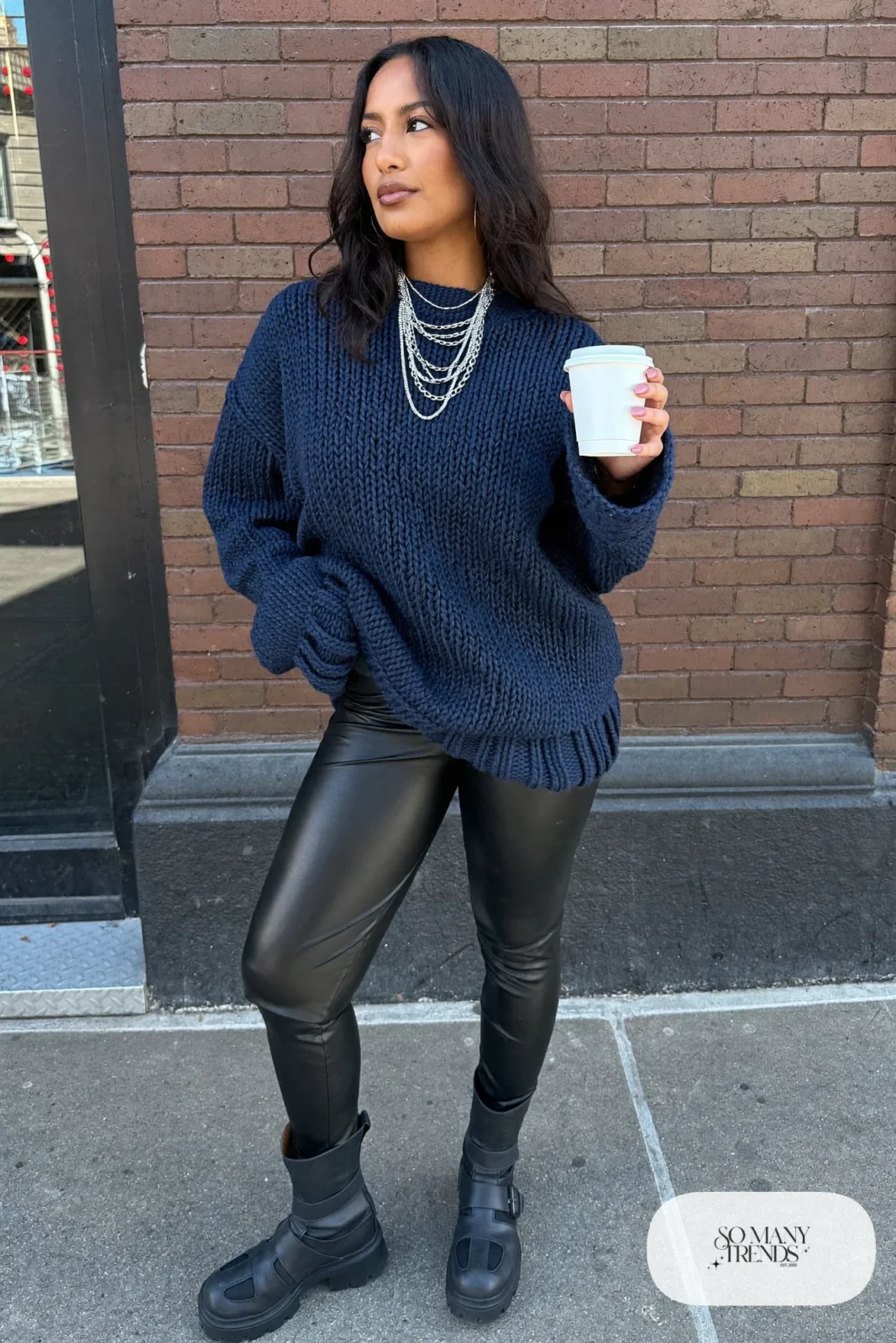 Woman in a navy oversized sweater, faux leather leggings, black beanie and chunky black boots, outfit 35