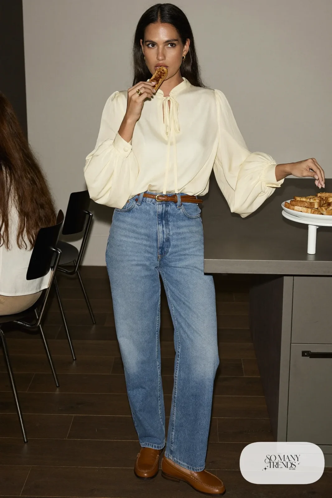 Woman in a cream blouse with soft sleeves, light baby blue jeans and tan loafers at a family brunch table, outfit 19