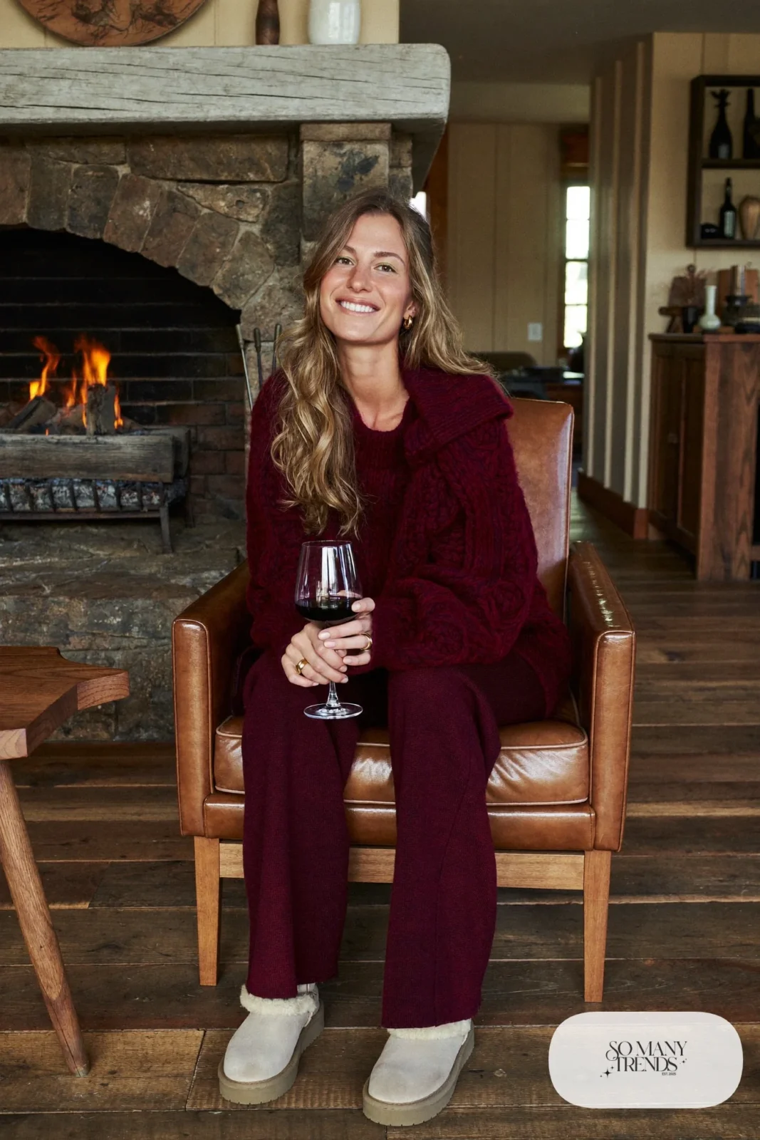 Woman in a burgundy chunky knit sweater and matching wide-leg knit pants with cream shearling boots, outfit 5