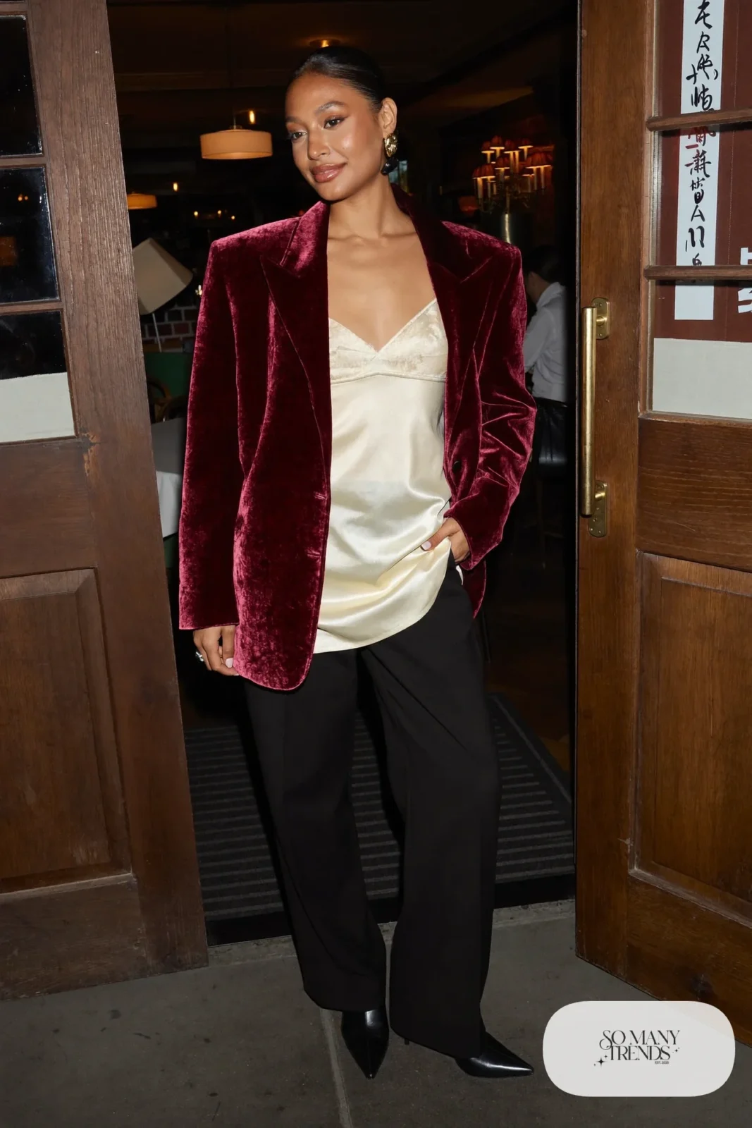 Woman in a burgundy velvet blazer, cream silk camisole, black wool trousers and black pointed boots, outfit 8