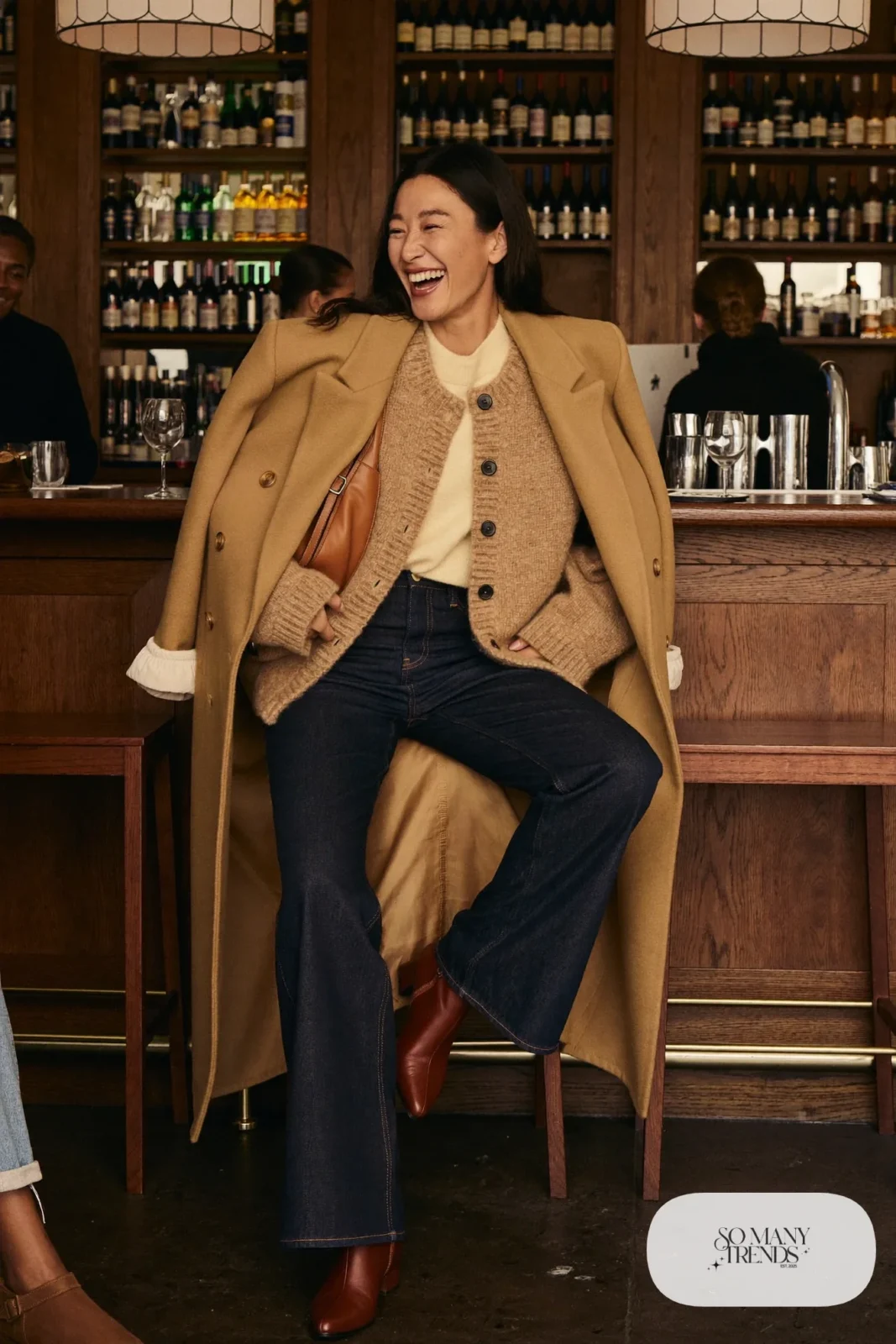 Woman in a chunky oatmeal cardigan, cream tee, dark flared jeans, brown leather boots and a cognac bag, outfit 27