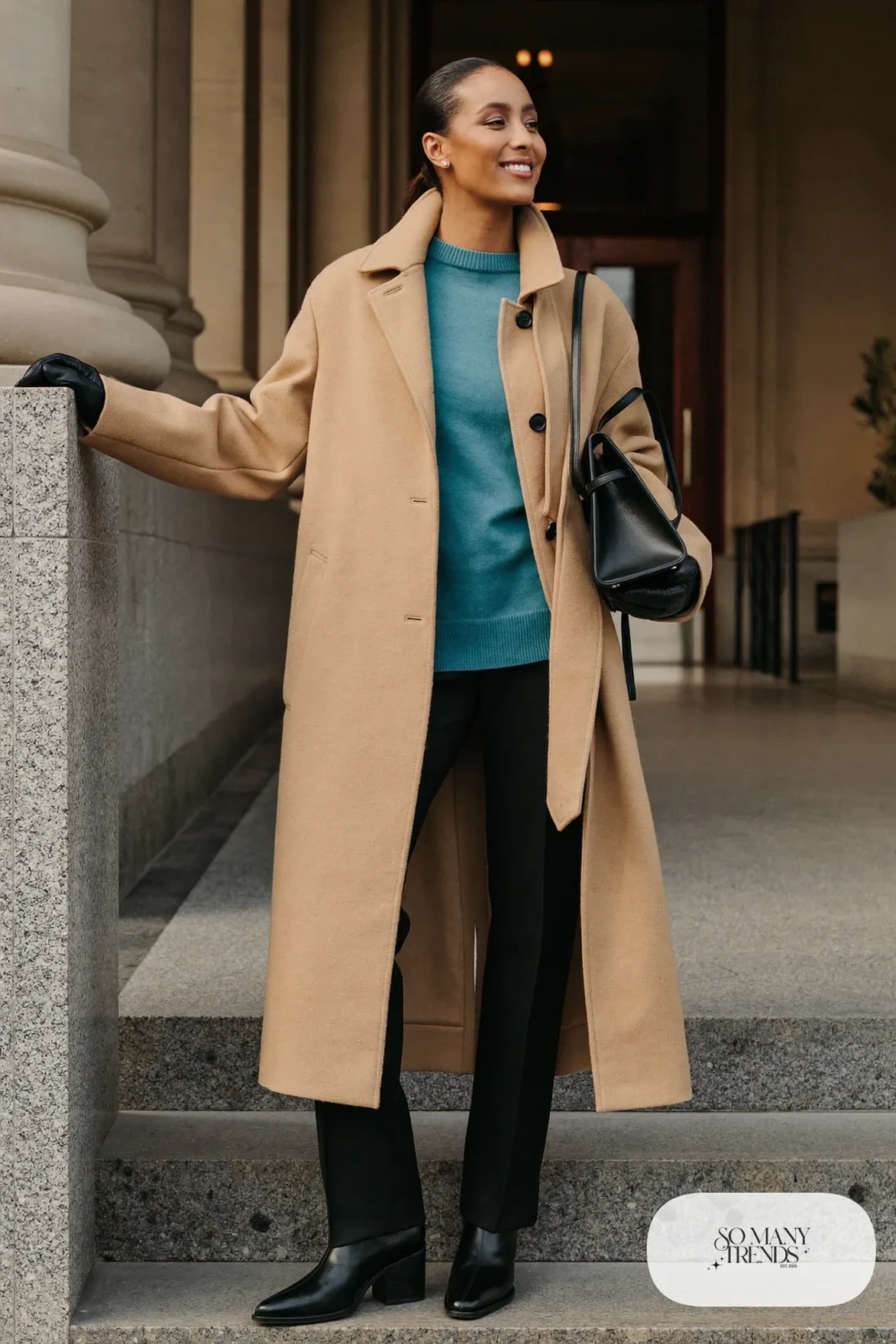Woman in a long camel wool coat, teal fine-knit sweater, black wide-leg pants and black leather ankle boots, outfit 1