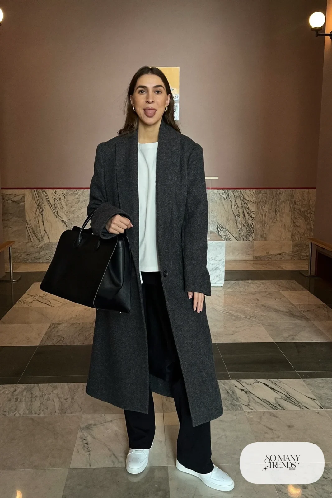 Woman in a long charcoal cardigan coat, white tee, black pants and white leather sneakers with a tote bag, outfit 5