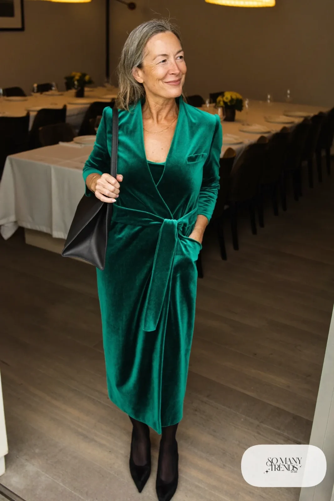 Woman in an emerald green velvet wrap midi dress, black opaque tights and black suede pumps, outfit 2