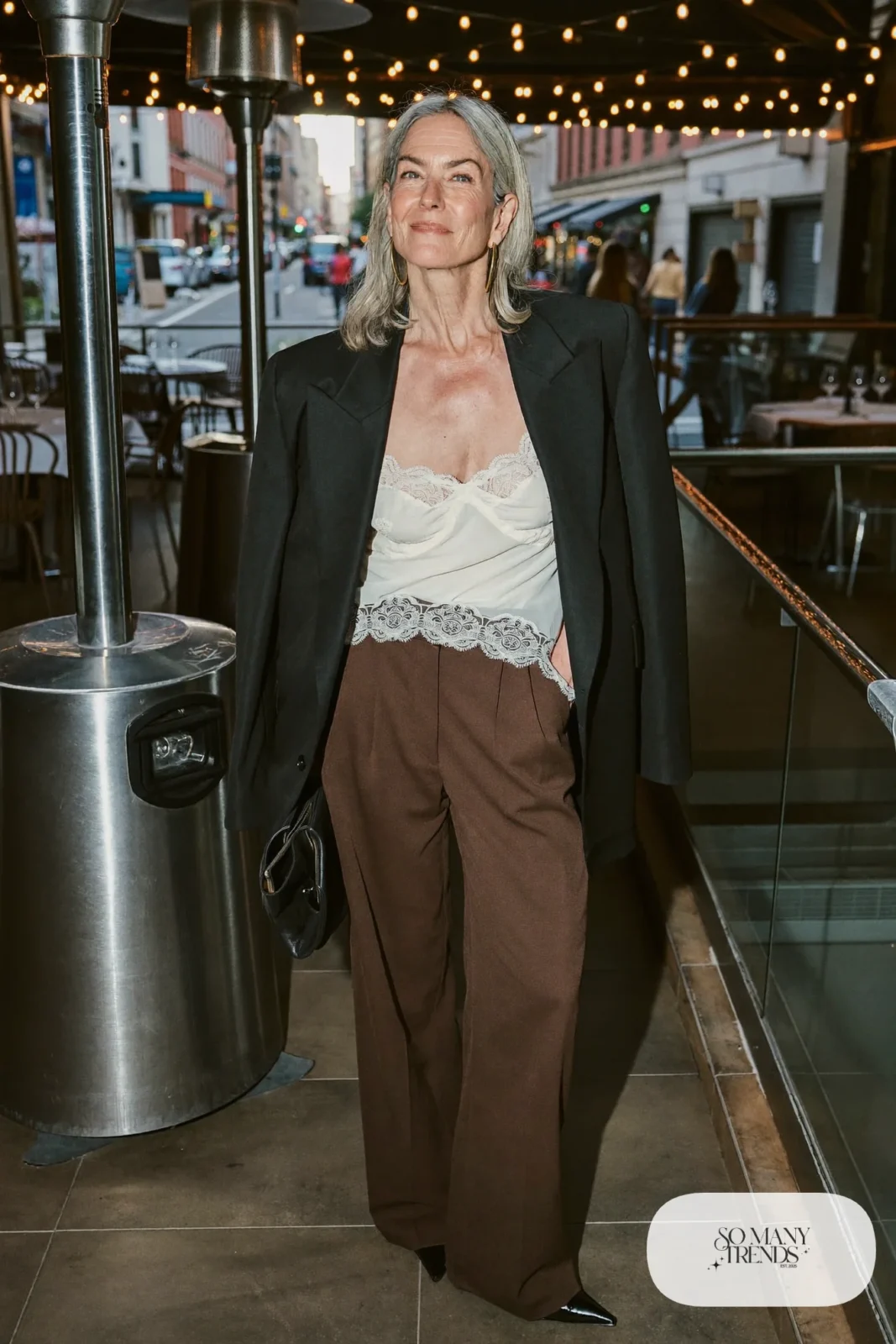 Woman in a cream lace camisole, chocolate brown wide-leg pants, black blazer and black pointed pumps, outfit 11