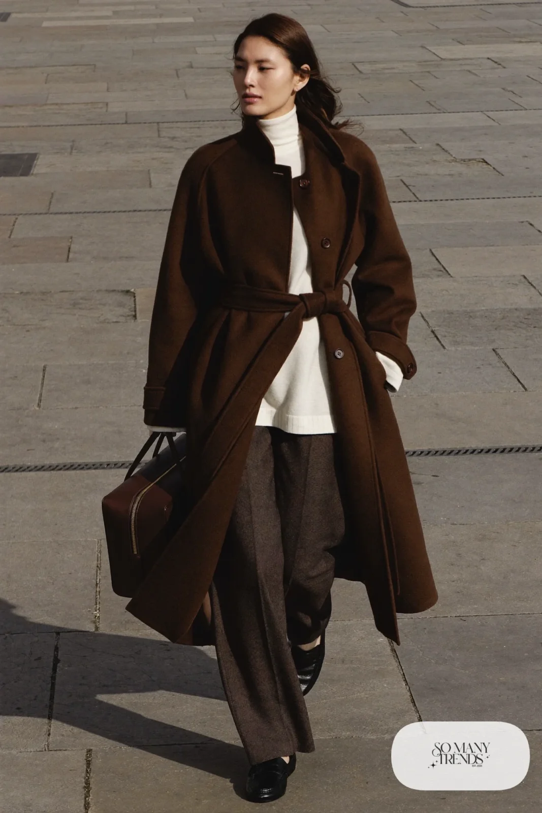 Woman in belted chocolate brown wool coat, cream turtleneck, wide-leg pants and loafers, outfit 7