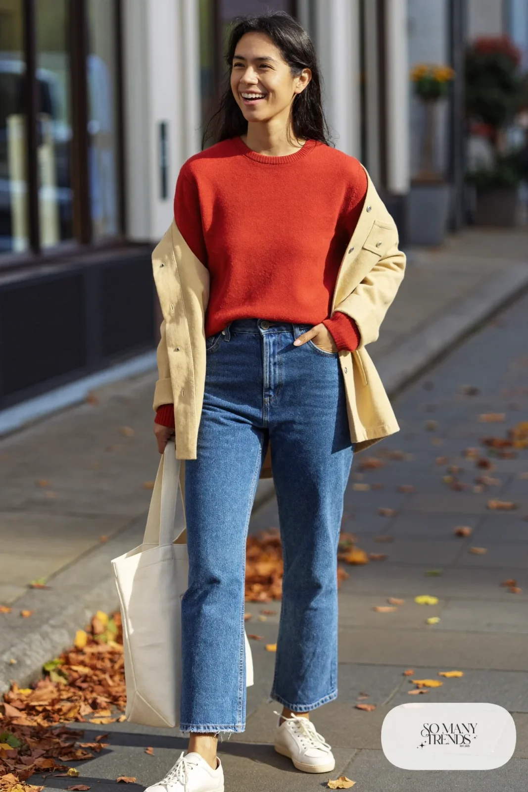 Woman in cropped straight jeans, tomato red knit sweater, cream leather low-top sneakers and camel jacket, outfit 12